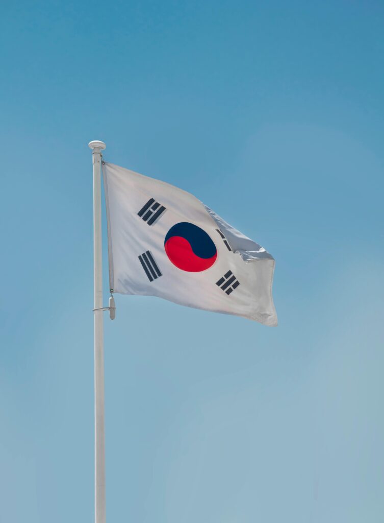 South Korean national flag fluttering on a flagpole against a clear blue sky in Seoul.